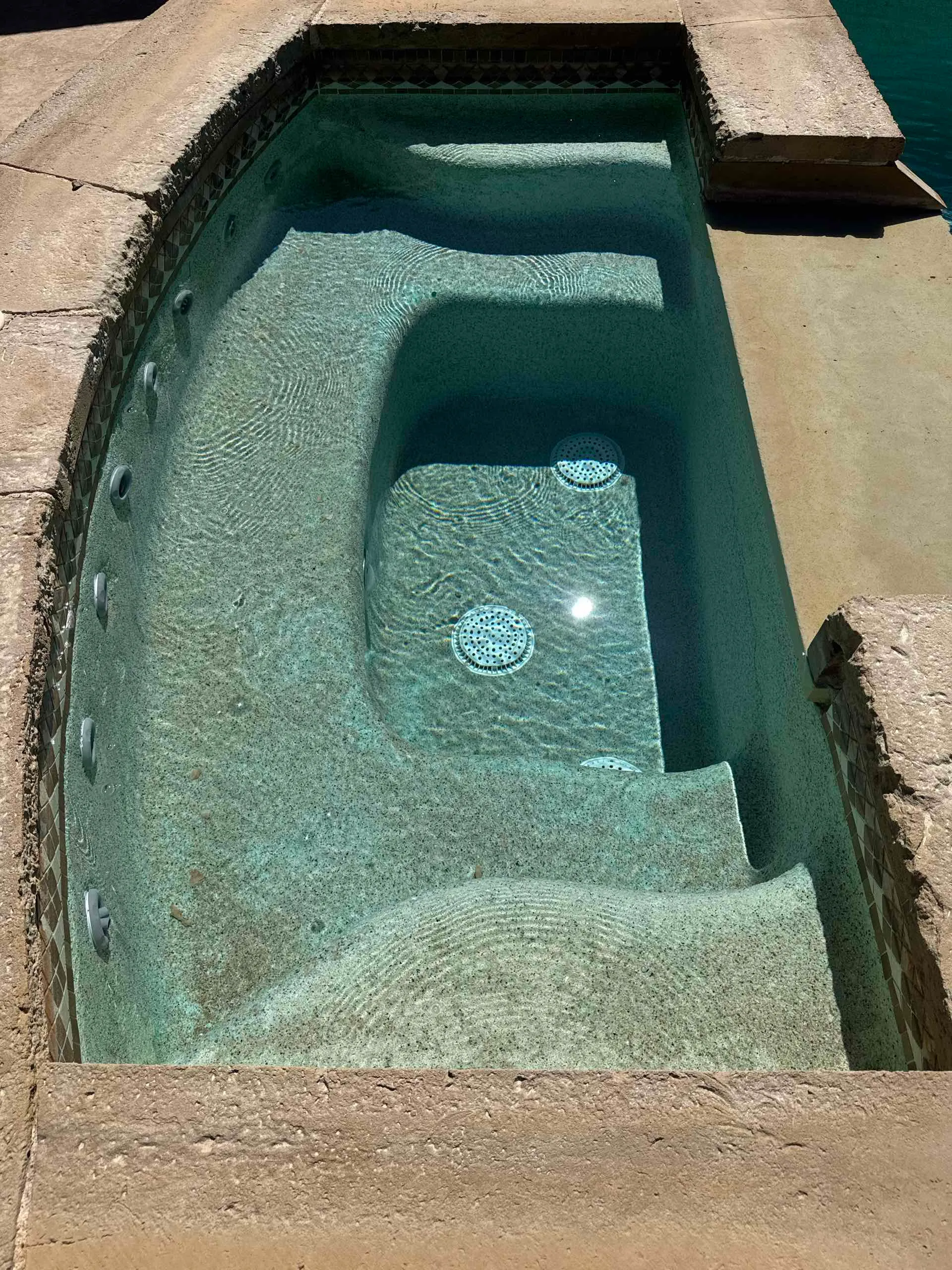 Before: Rectangular spa with steps, water and a light interior finish